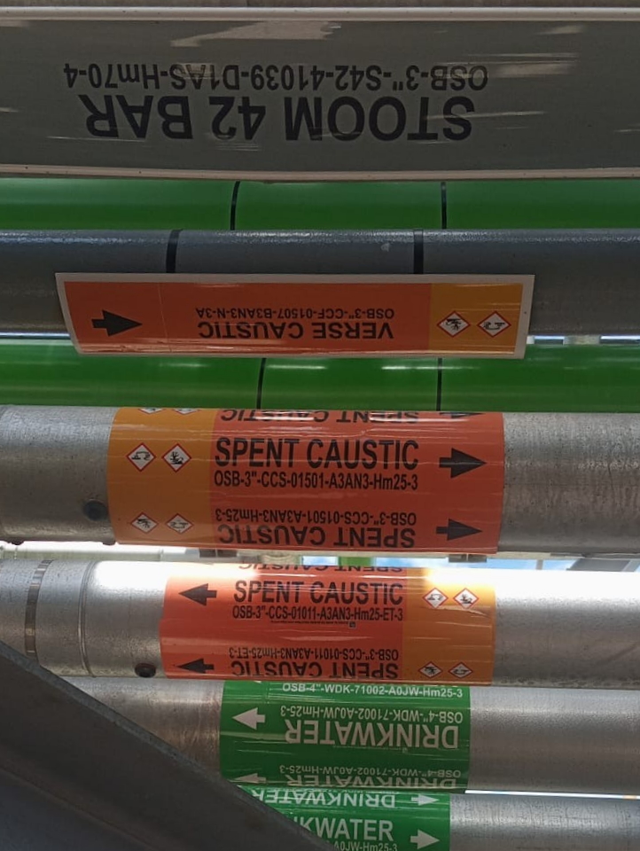 Wrap-around pipe markers being installed on industrial pipeline for safety compliance